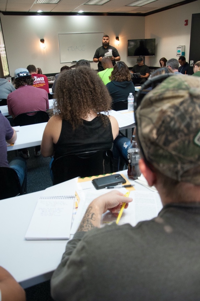 Diverse group of USS Academy students taking notes during classroom firearms training