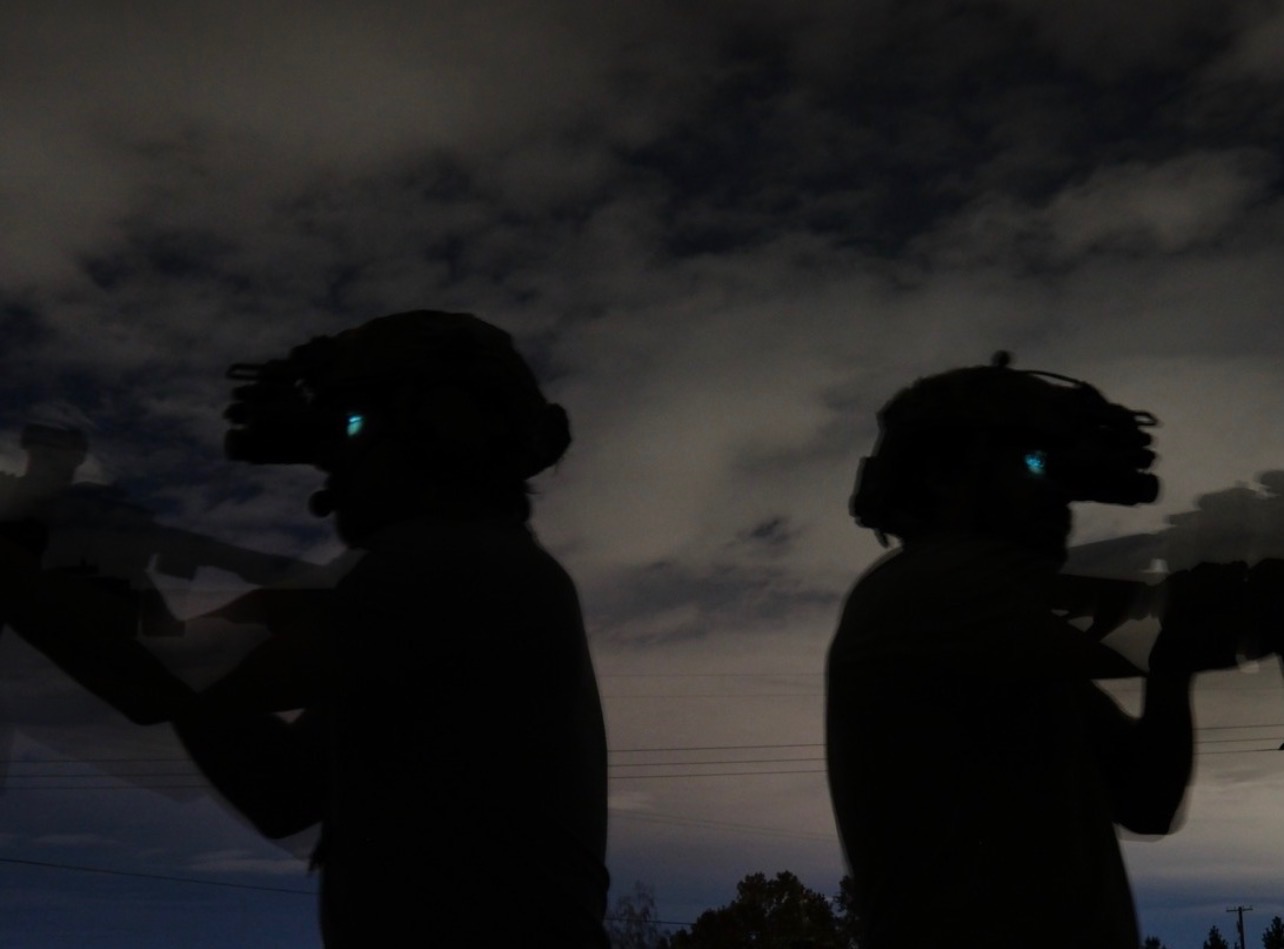 Two USS Academy operators with night vision goggles glowing at dusk