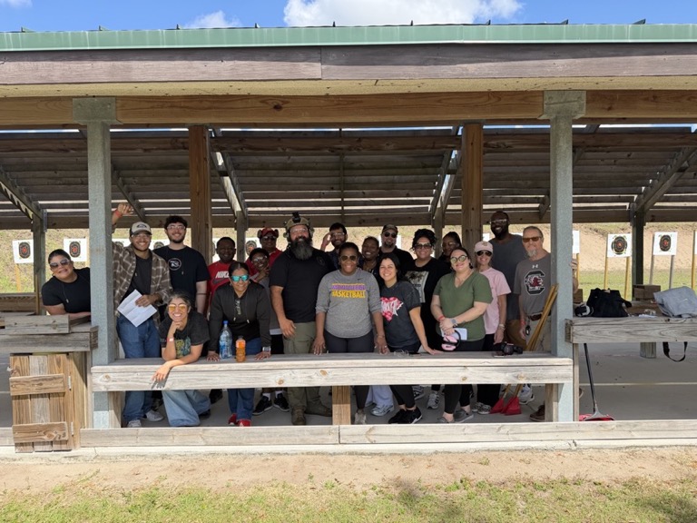 USS Academy class of 20+ diverse students and instructors at outdoor shooting range