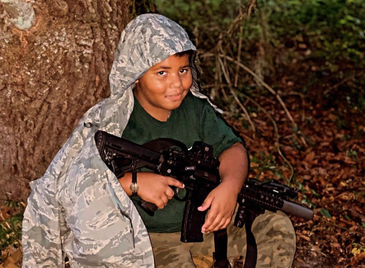 Young student in camouflage with rifle during USS Academy family firearms introduction class